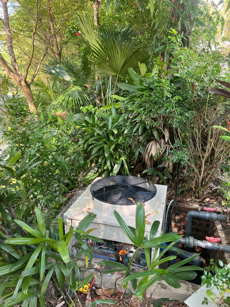 Sửa Heat Pump bể bơi Sirac: cụm máy ngoài trời cạnh cây xanh và đường nước